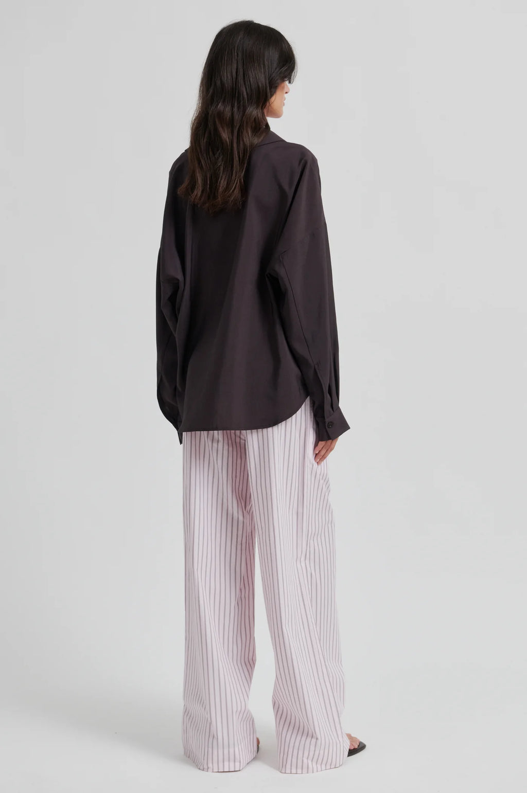 Person wearing a black shirt and white striped pants on a light gray background