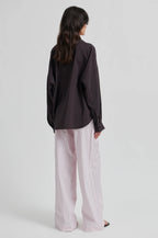 Person wearing a black shirt and white striped pants on a light gray background