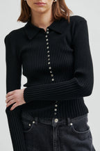 Black ribbed sweater with button details worn by a person on a white background