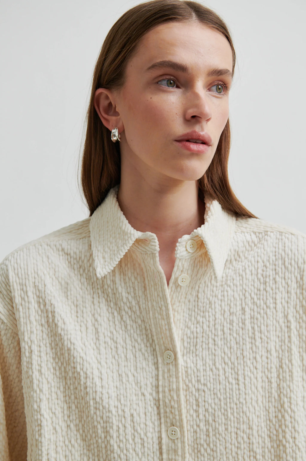 Woman wearing a textured beige shirt against a plain background
