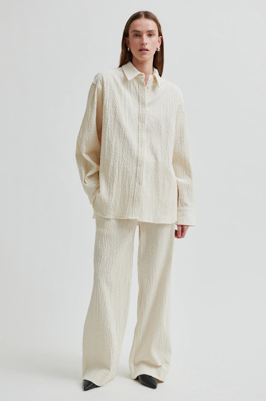Person wearing a cream-colored outfit on a white background