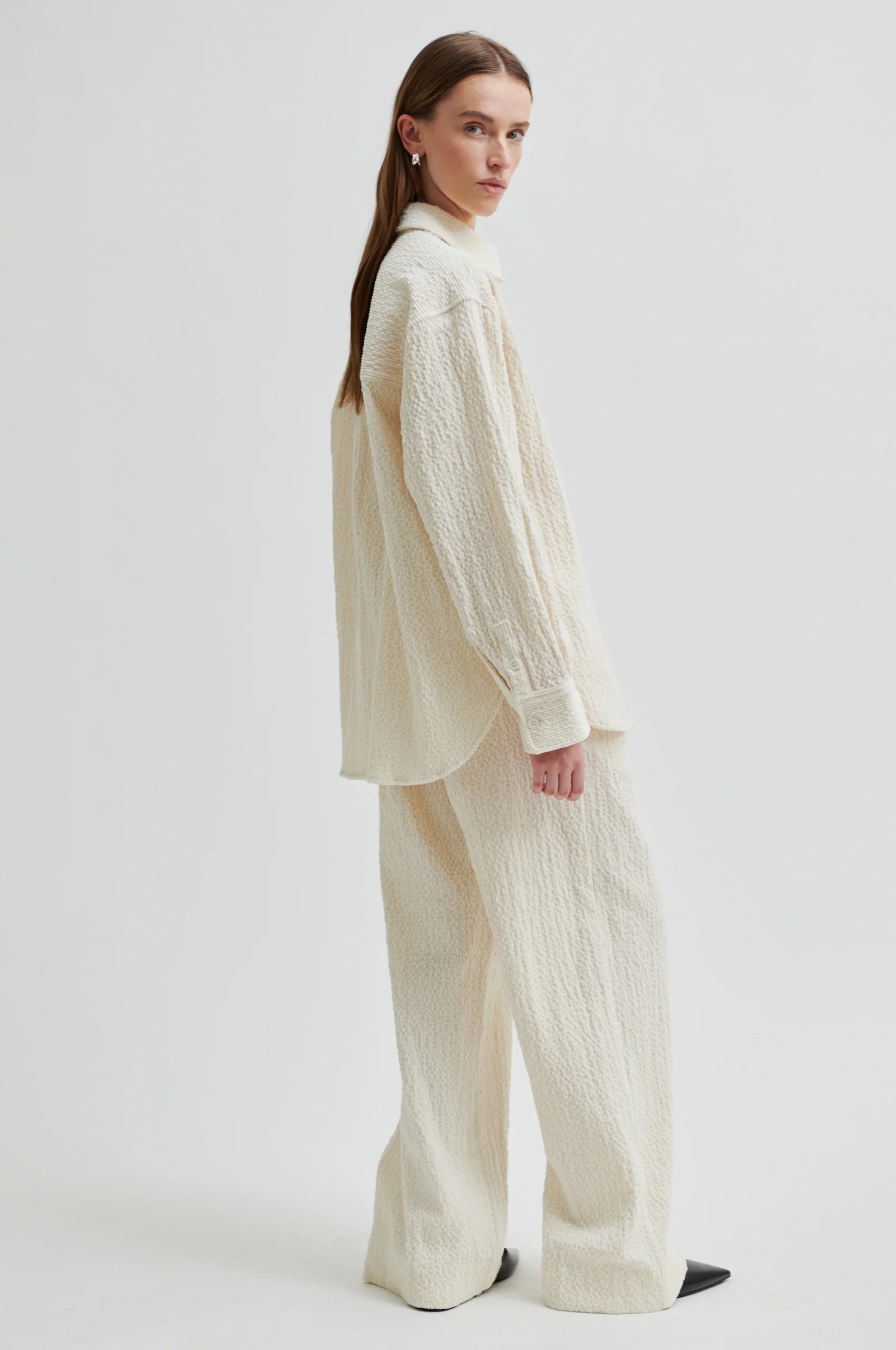 Woman wearing a cream-colored outfit on a white background