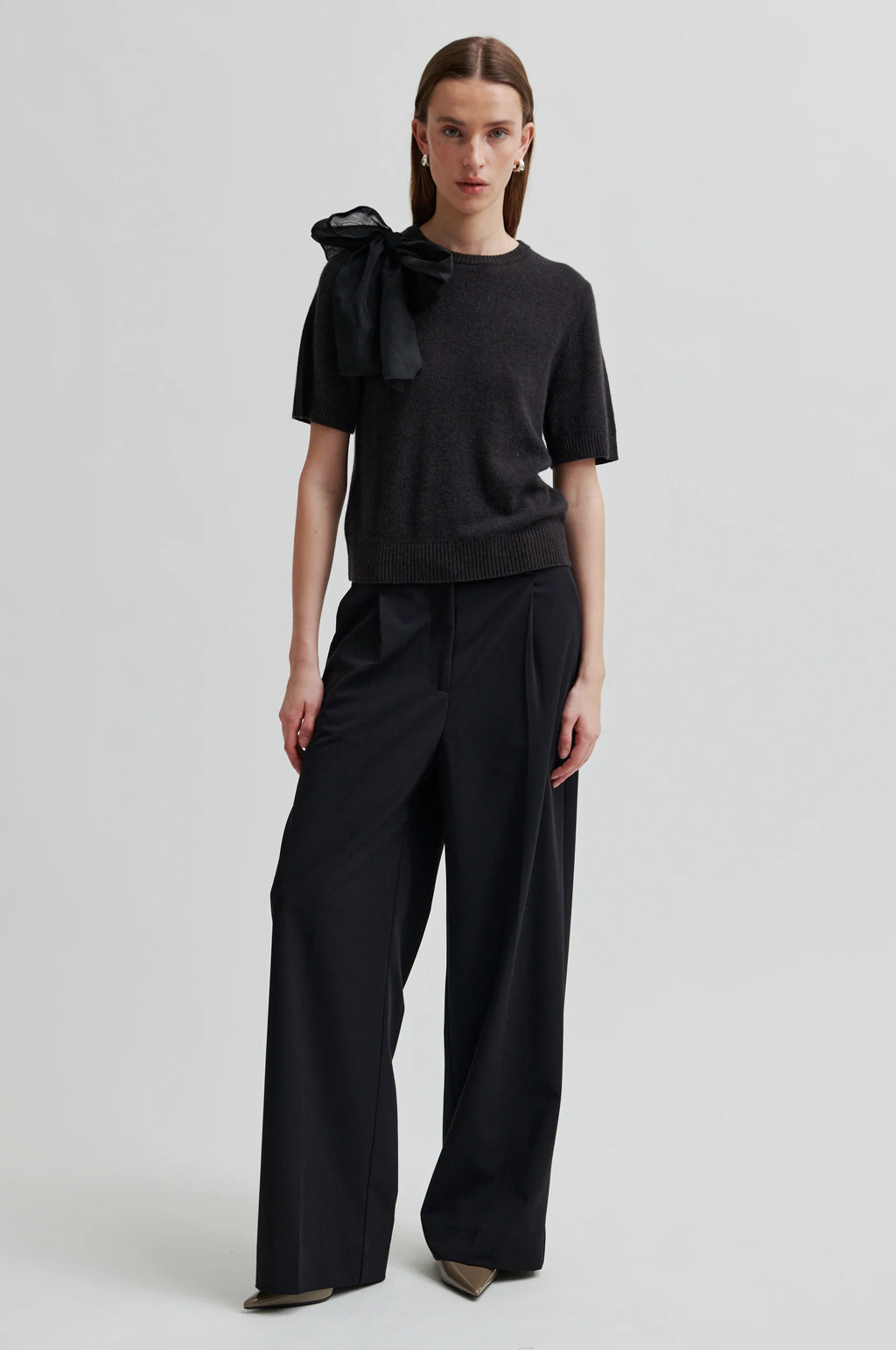 Woman wearing a black outfit with a bow detail on a white background