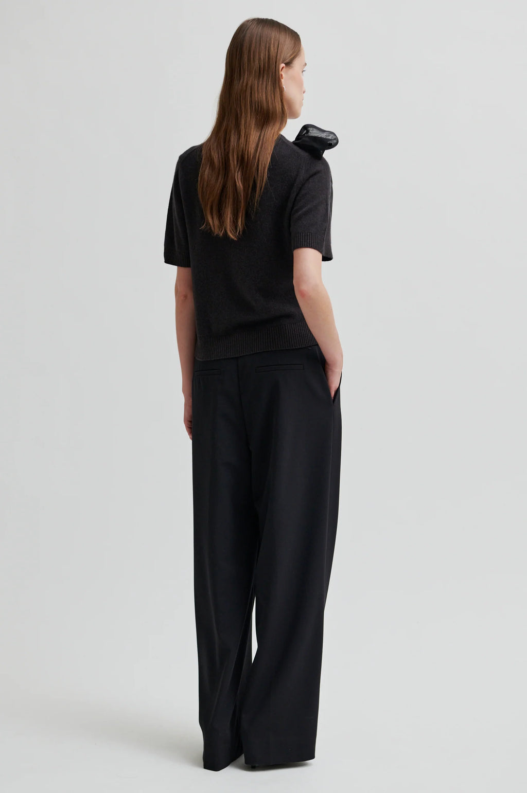Person wearing a black outfit on a light gray background