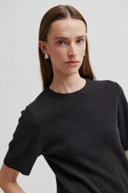 Woman wearing a black sweater against a plain background