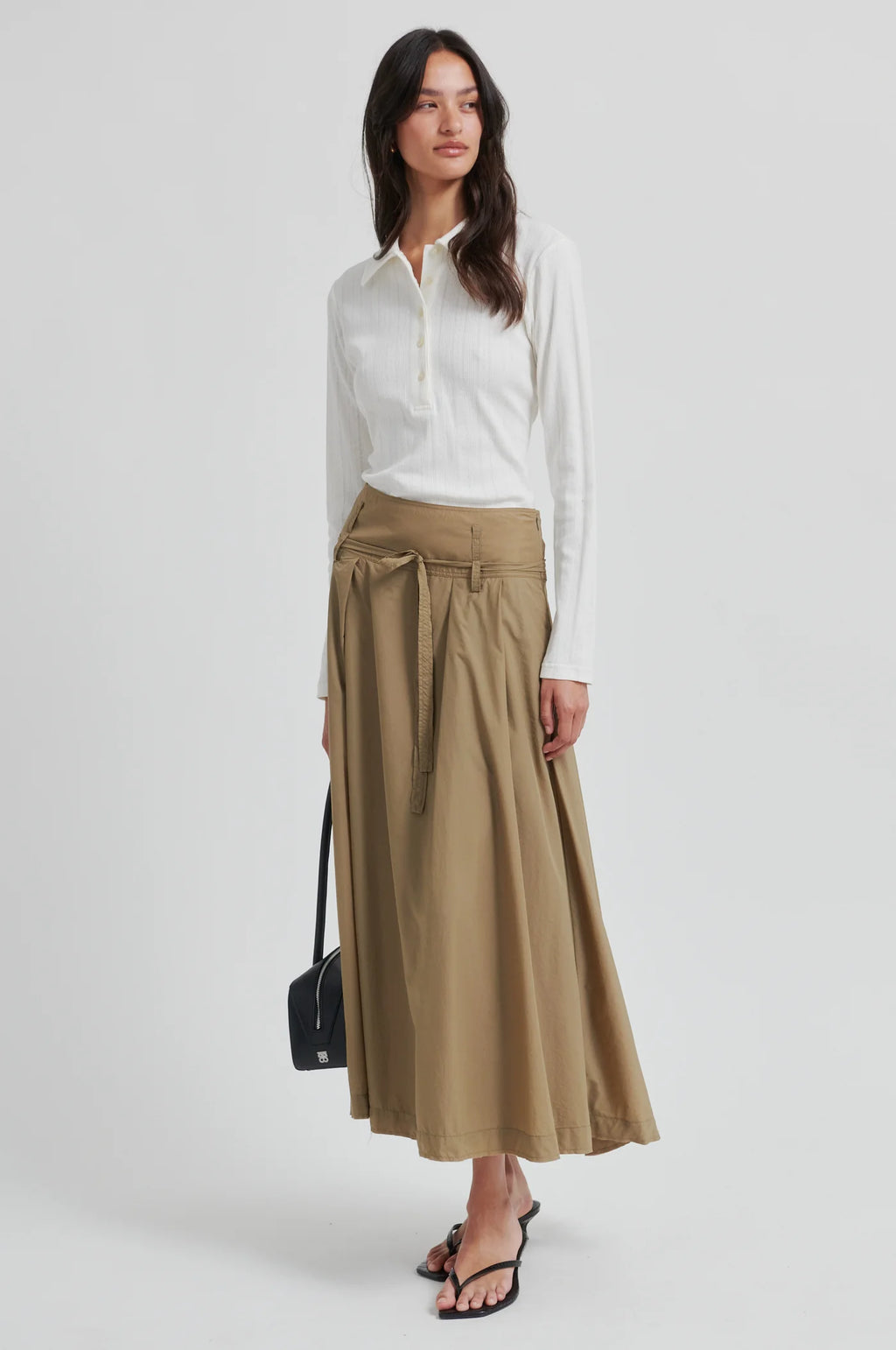 Woman wearing a white blouse and beige skirt on a white background