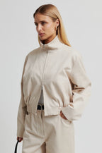 Woman wearing a beige jacket and pants on a plain background
