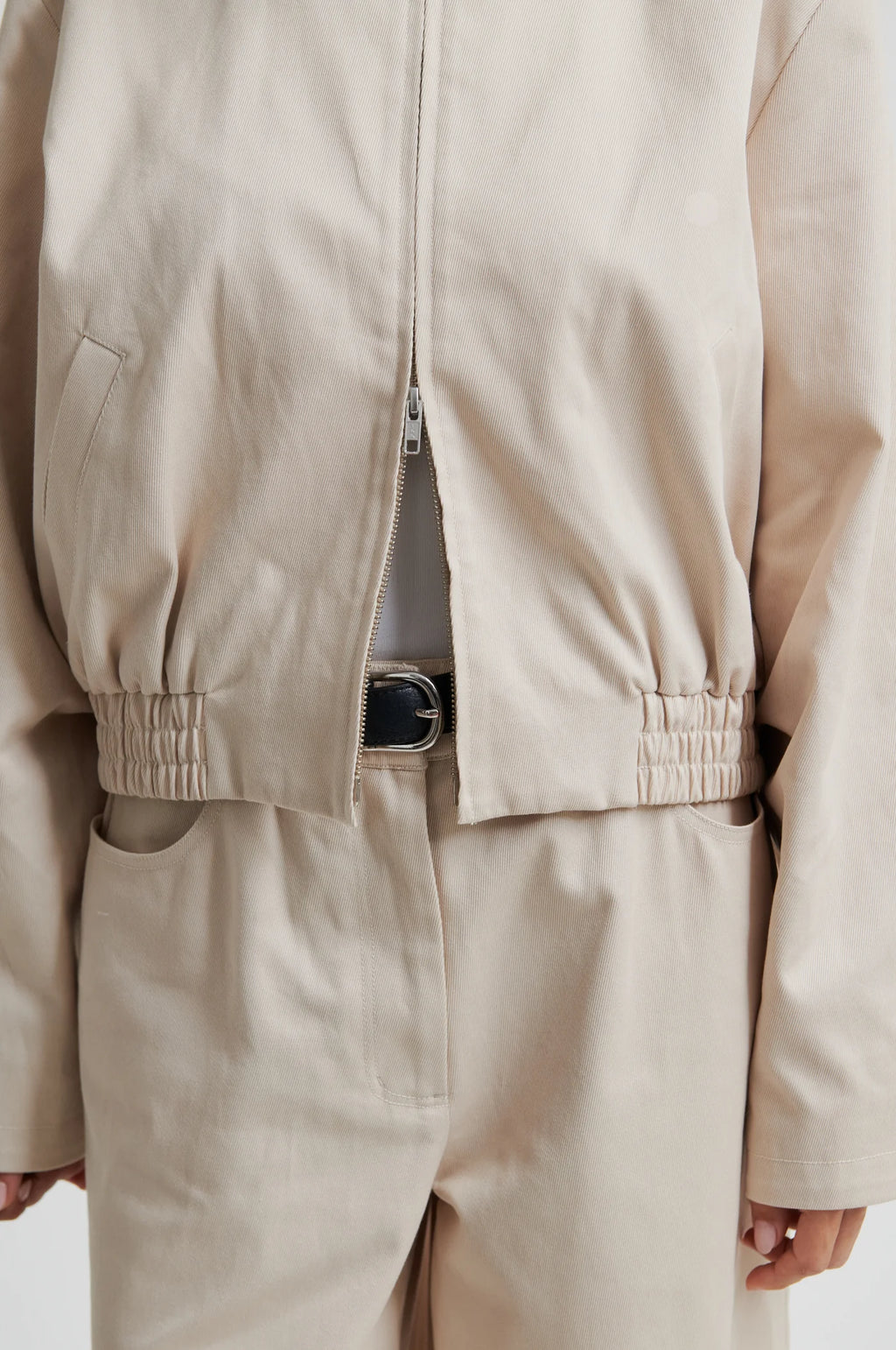 Beige jacket and pants worn by a person on a plain background