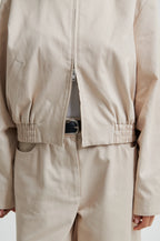 Beige jacket and pants worn by a person on a plain background