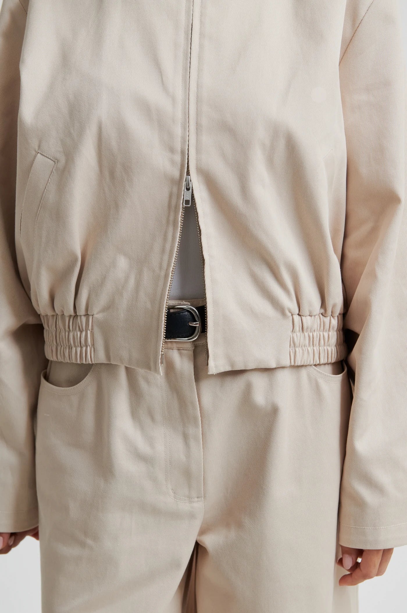 Beige jacket and pants worn by a person on a plain background