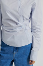Light blue button-up shirt and blue jeans on a plain background