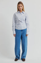 Woman wearing a light blue shirt and jeans on a white background