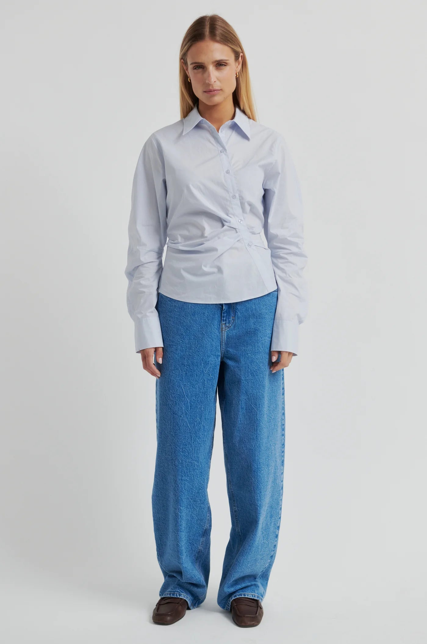 Woman wearing a light blue shirt and jeans on a white background