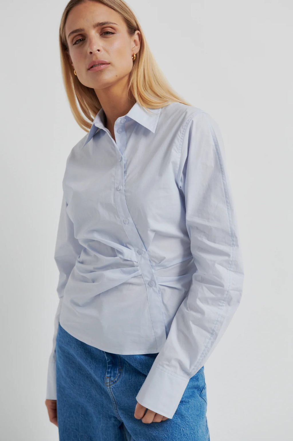 Woman wearing a light blue shirt with a tie-waist design on a white background