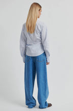 Person wearing a light gray shirt and blue jeans on a white background