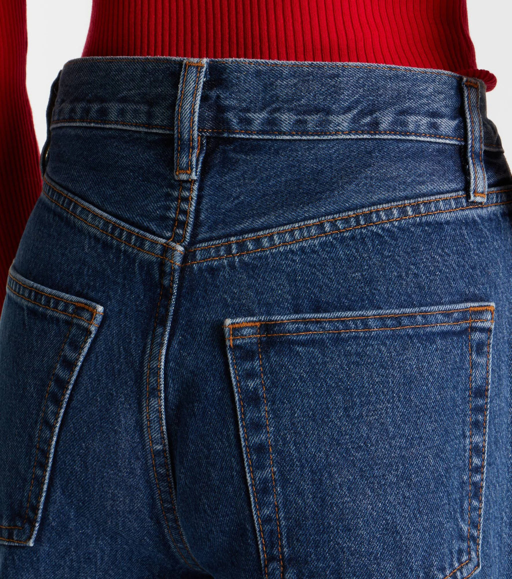 Close-up of blue jeans with a red sweater in the background