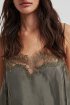 Woman wearing a green slip dress with lace detailing