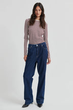 Woman wearing a striped shirt and blue jeans on a white background