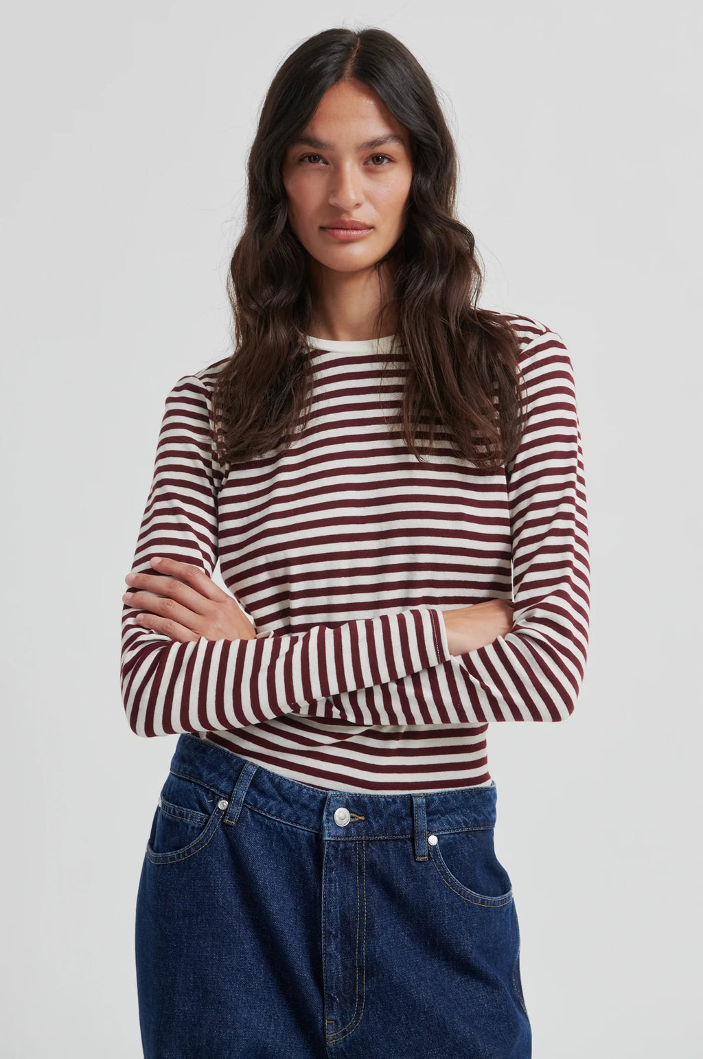 Woman wearing a striped shirt and jeans on a plain background