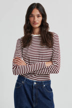 Woman wearing a striped shirt and jeans on a plain background
