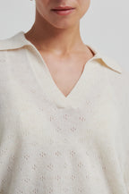 Close-up of a person wearing a white blouse with a V-neck and small floral patterns.