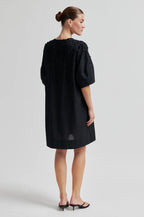 Woman wearing a black dress against a white background