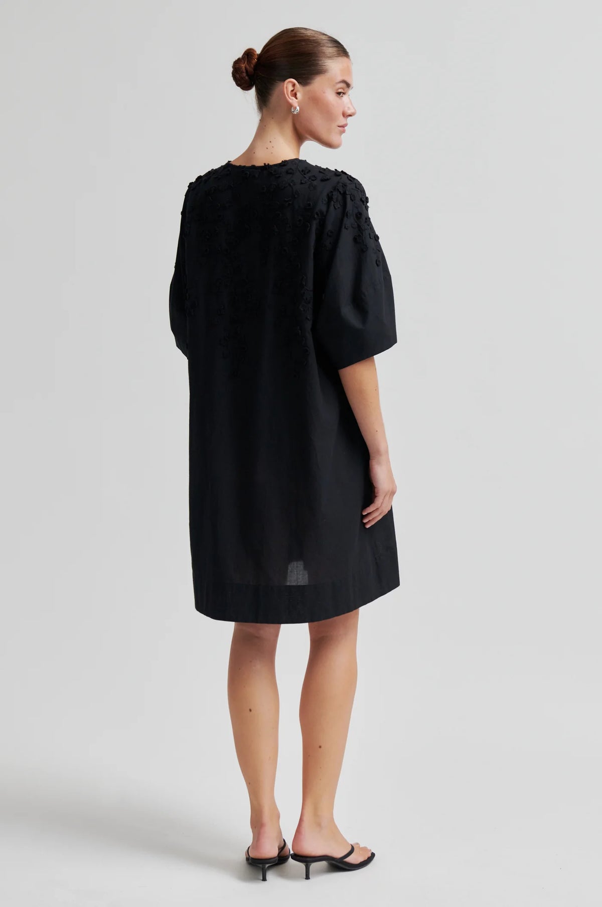 Woman wearing a black dress against a white background