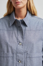 Close-up of a person wearing a blue and white striped shirt with a neutral background