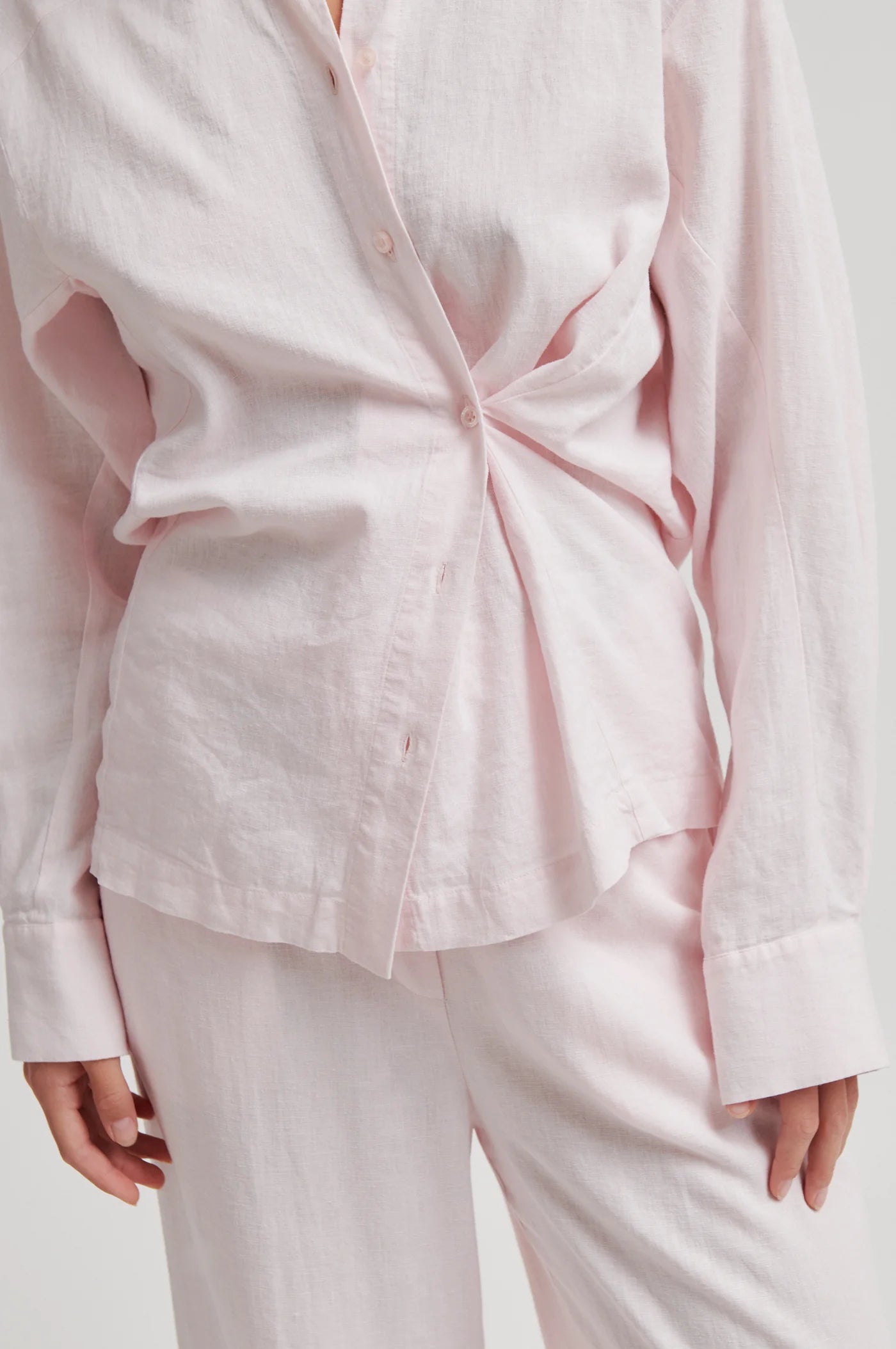 Light pink shirt with a tie detail worn by a person on a white background