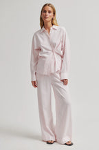 Woman wearing a light pink shirt and pants set on a white background