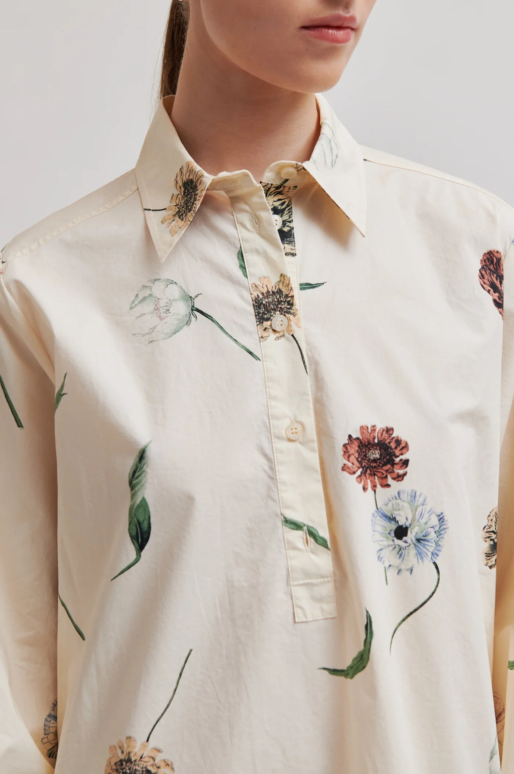Close-up of a person wearing a floral-patterned shirt with a neutral background