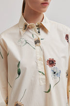 Close-up of a person wearing a floral-patterned shirt with a neutral background