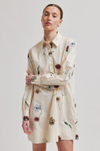 Woman wearing a beige floral dress against a plain background