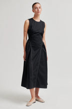 Woman wearing a black sleeveless dress on a plain background