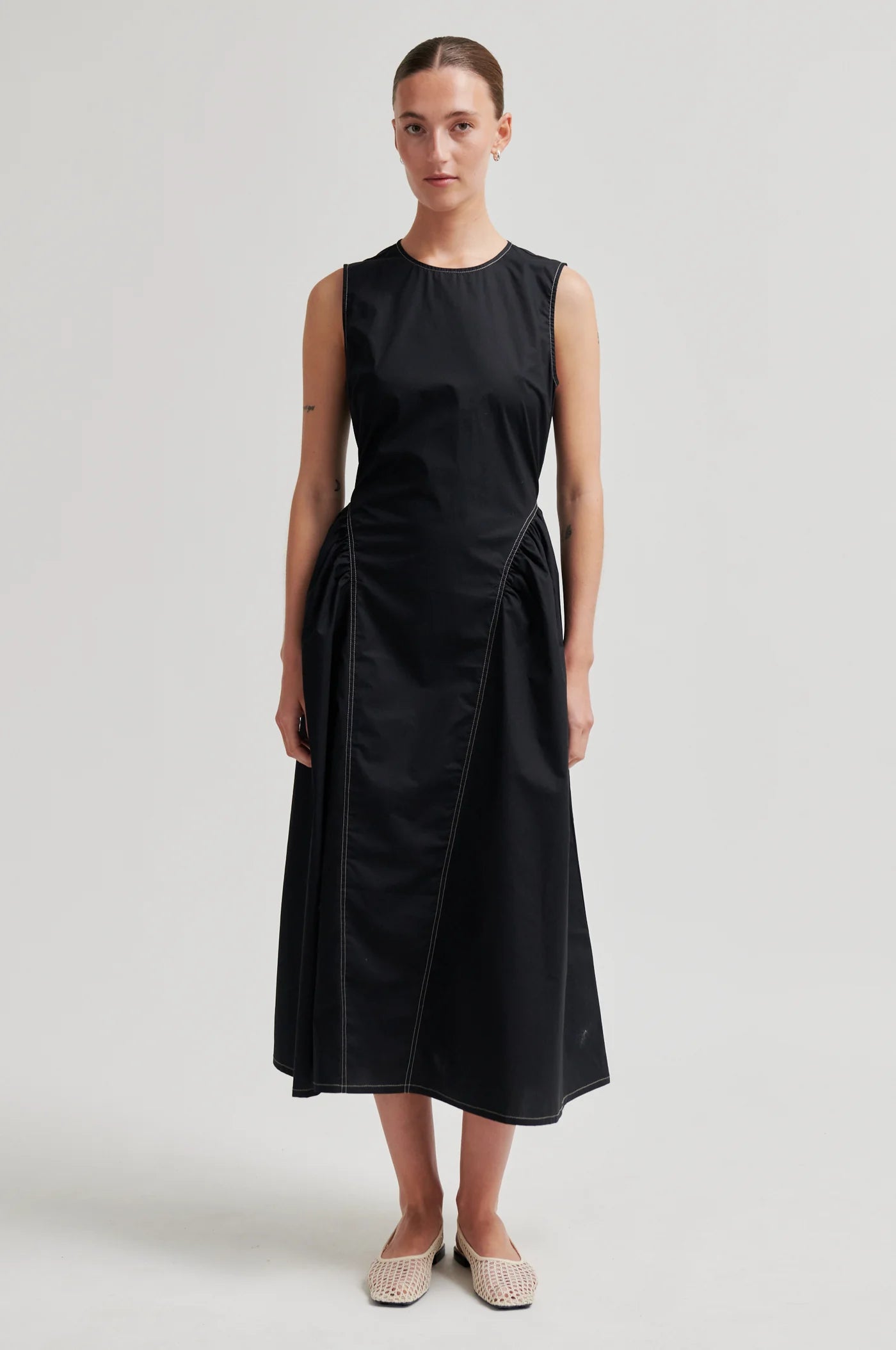 Woman wearing a black sleeveless dress on a white background