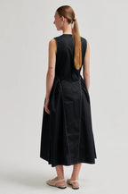 Woman wearing a black sleeveless dress on a plain background