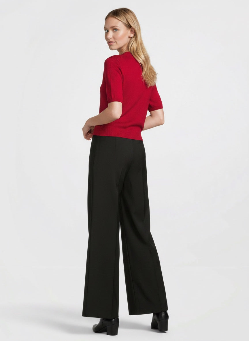 Woman wearing a red top and black pants on a white background
