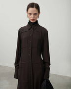 Woman wearing a dark brown coat against a plain background