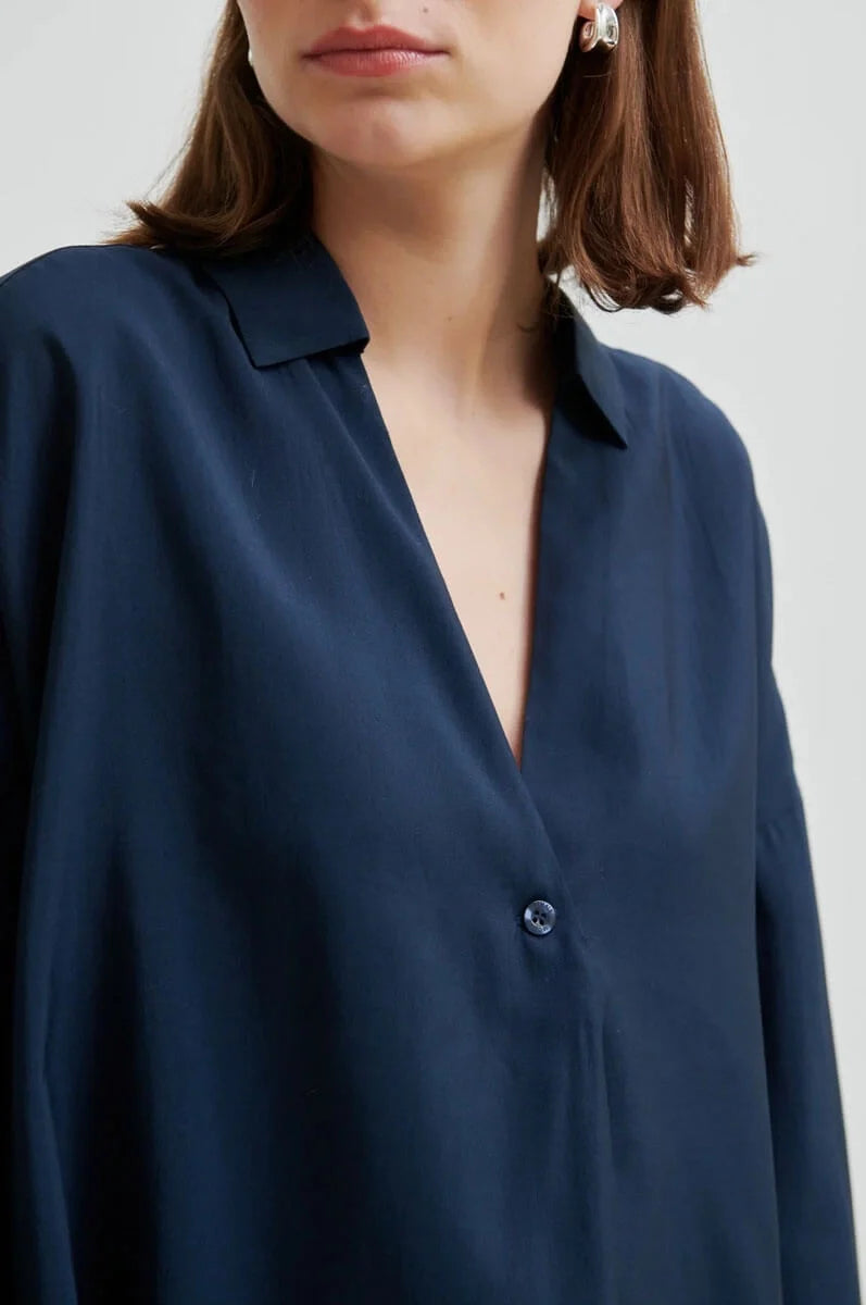 Navy blue shirt worn by a person on a white background