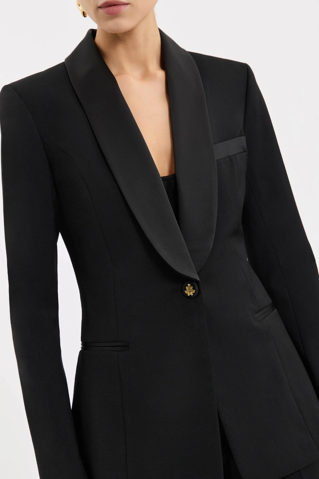 Black suit jacket with a gold button on a white background