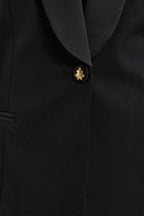 Close-up of a black suit jacket with a gold button on a black background