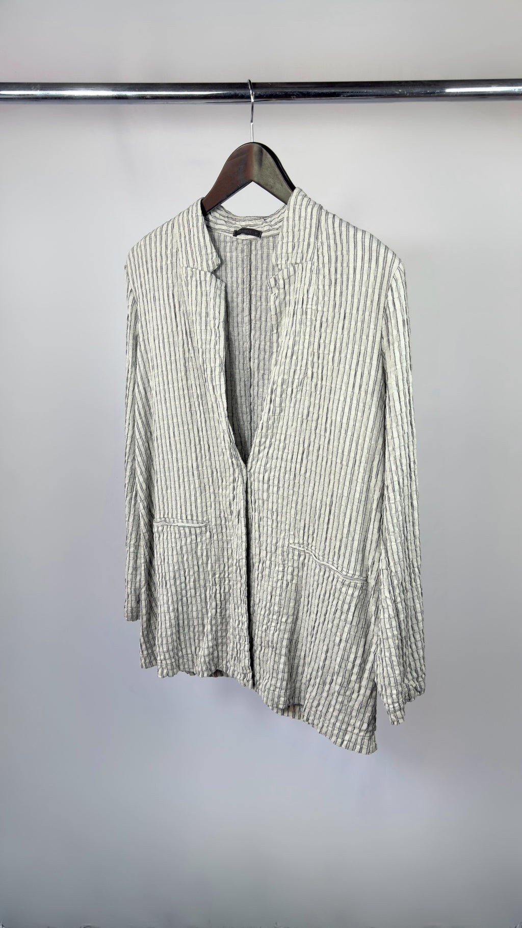 Green and white striped shirt on a hanger against a plain background