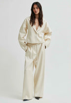 Woman wearing a cream satin suit against a white background
