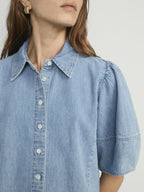 Light blue denim shirt worn by a person on a plain background