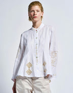 Person wearing a white embroidered shirt on a plain background