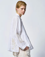 Person wearing a white embroidered shirt on a plain background