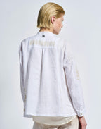 Person wearing a white embroidered shirt on a plain background