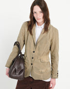 Woman wearing a beige blazer holding a brown leather bag on a white background