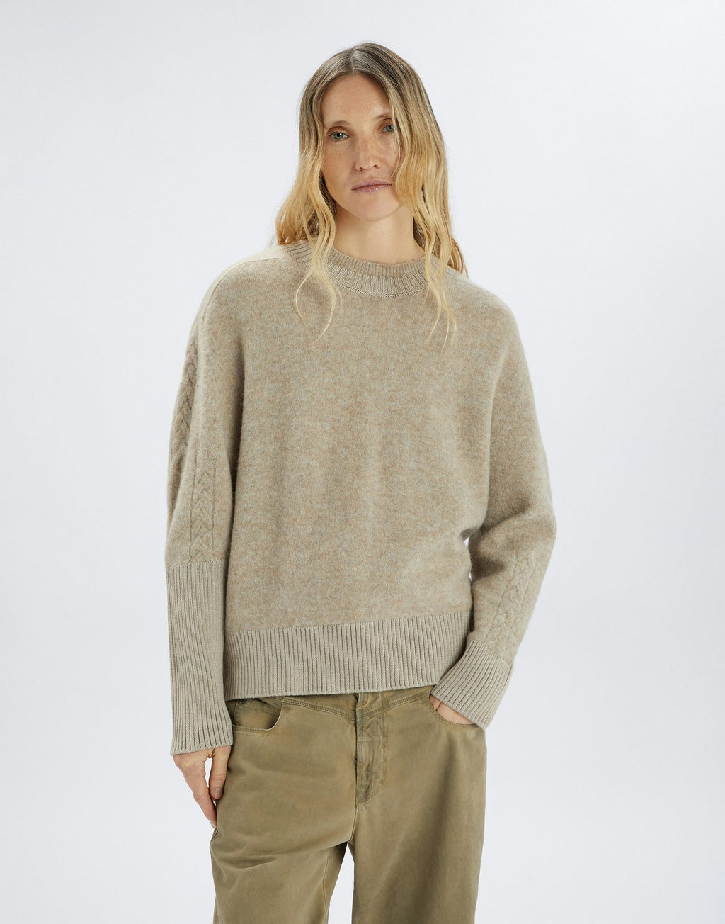Woman wearing a beige sweater and pants on a white background