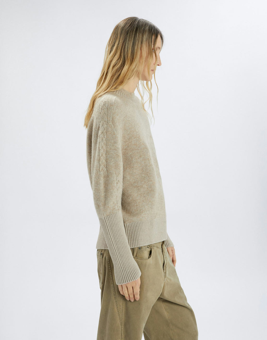 Woman wearing a beige sweater and beige pants on a white background